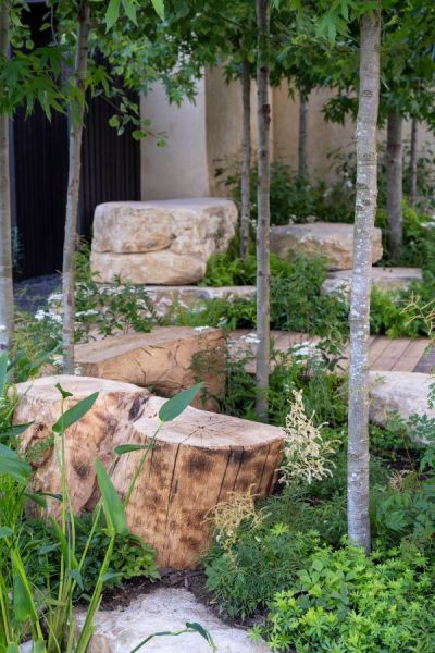 Chunky logs and stone used as natural seating in the America's Wild garden at RHS Hampton 2023.