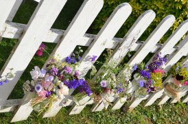 Jam jar flowers on a picket fence.